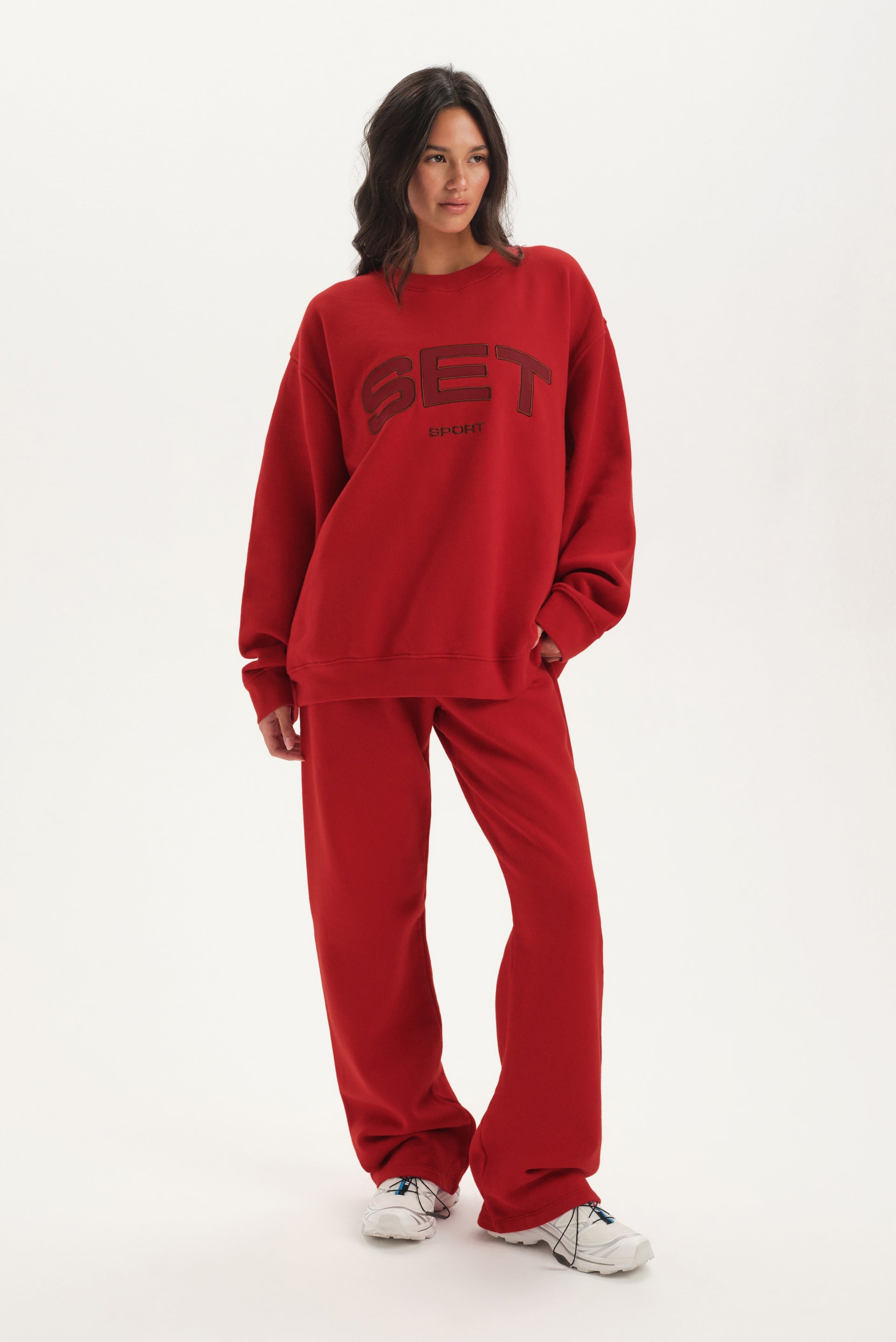 Person wearing a red 'SET' sweatshirt and pants on a white background