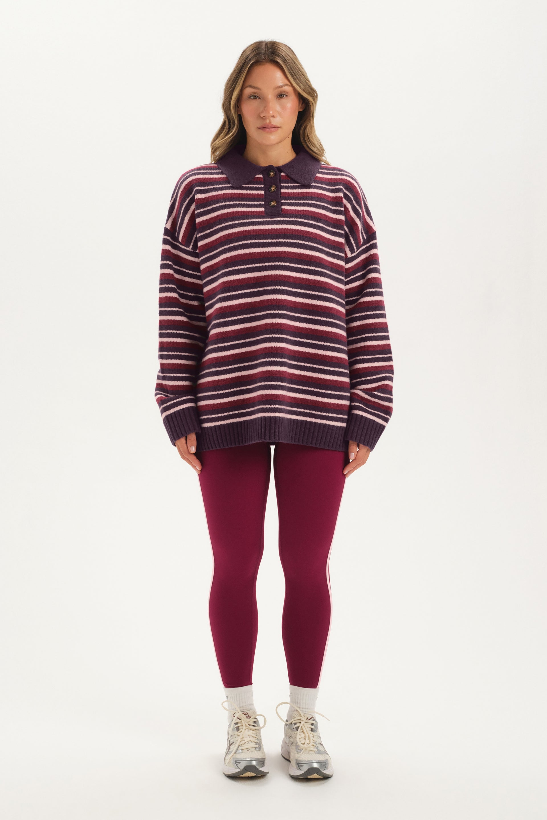 Woman wearing a striped sweater and leggings on a white background