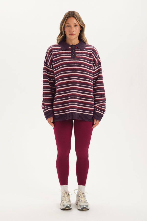 Woman wearing a striped sweater and leggings on a white background