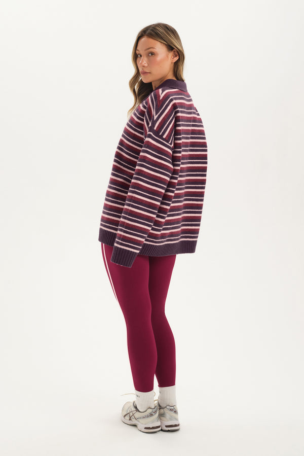 Woman wearing a striped sweater and red leggings on a white background