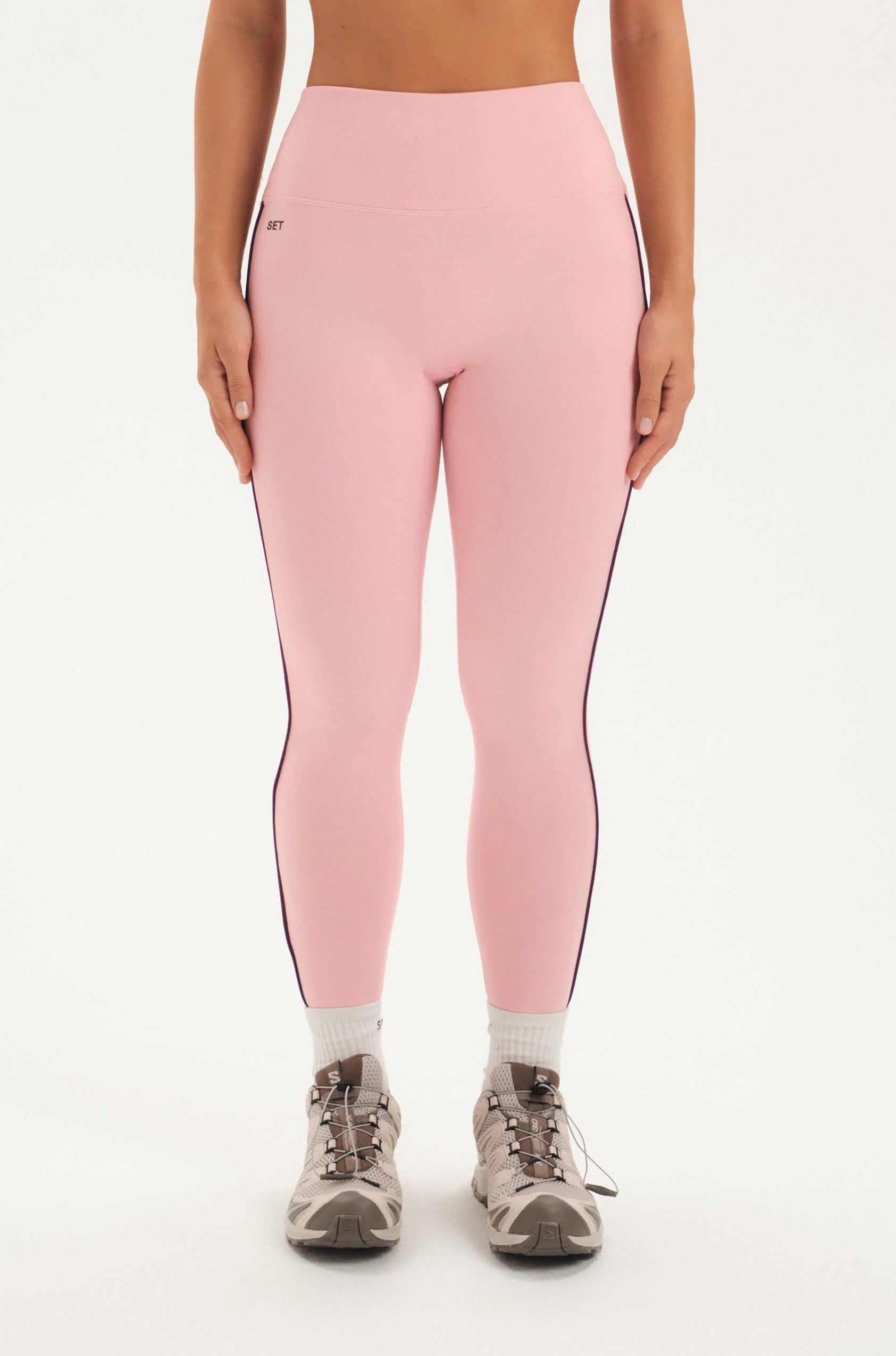 Woman wearing pink leggings set on a white background <model-info>Bre wears a size M and is 5’7”, 25½" waist, 33” bust.</model-info>