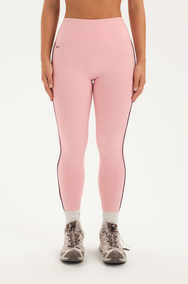 Woman wearing pink leggings set on a white background 