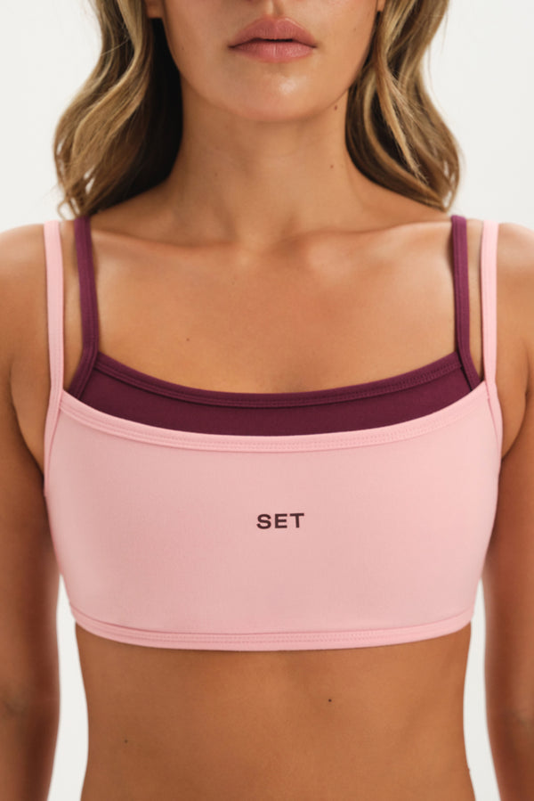 Pink sports bra with maroon straps and 'SET' logo on a white background