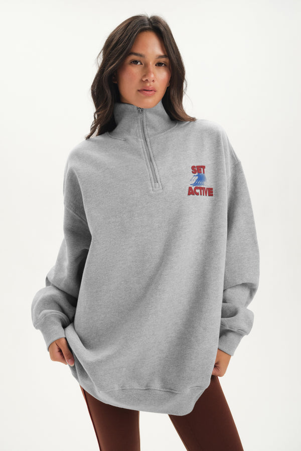 Person wearing a gray sweatshirt with a logo on a white background 
