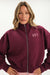 Woman wearing a maroon zip-up hoodie with 'SET' logo on a white background <model-info>Bre wears a size M and is 5’7”, 25½" waist, 33” bust.</model-info>