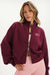 Woman wearing a maroon jacket with 'SET' logo on a white background
