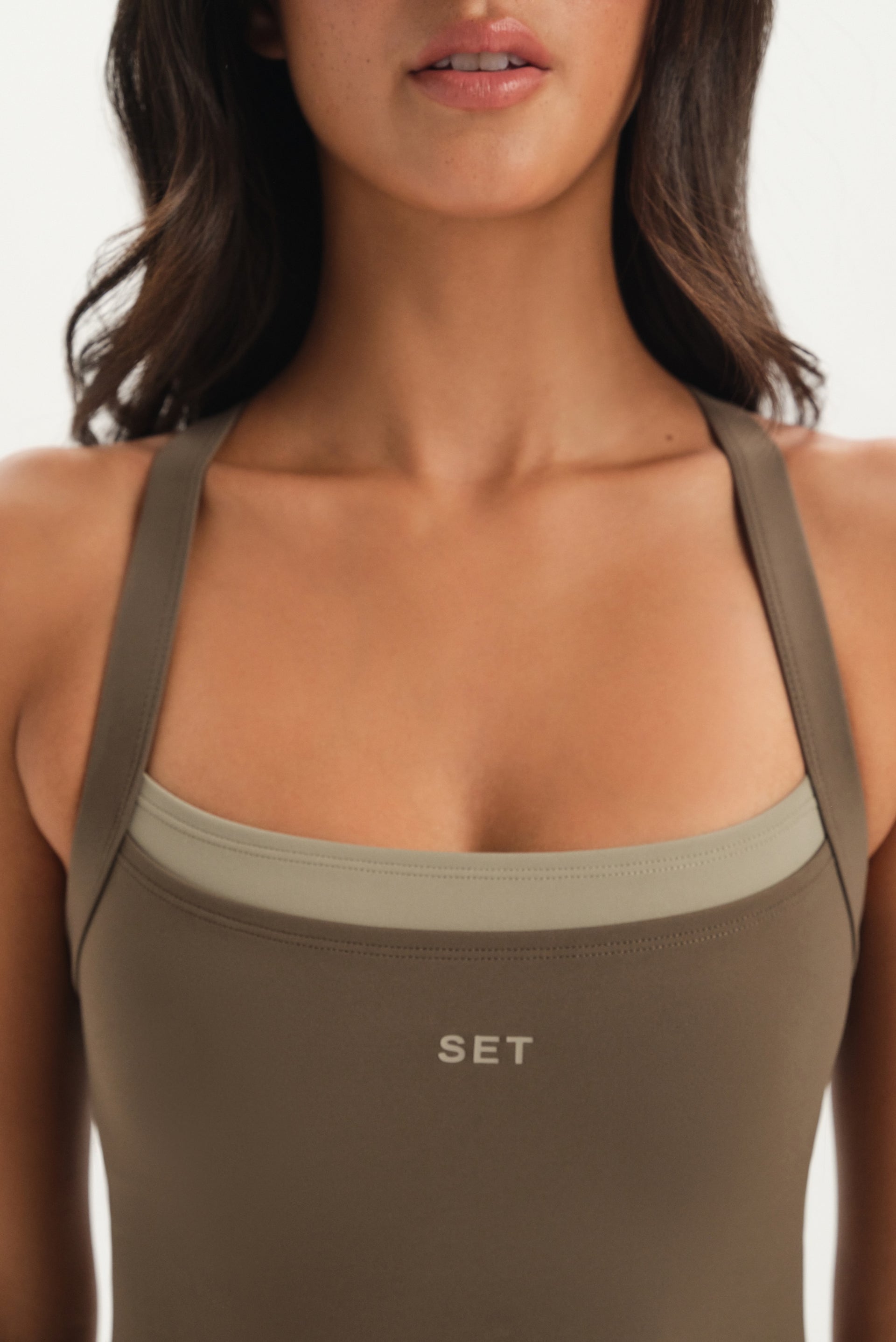 Woman wearing a brown tank top with 'SET' branding on a white background