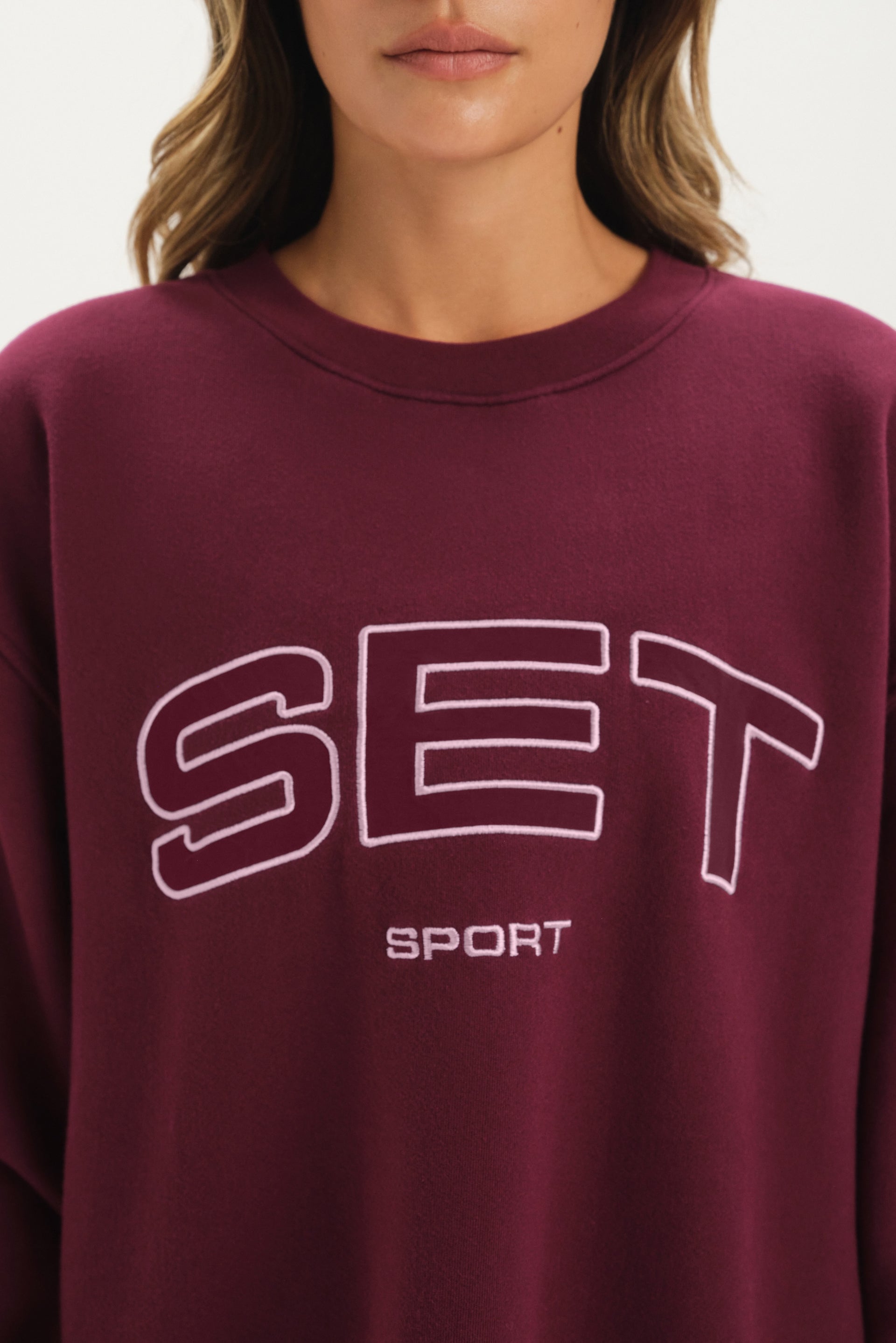Maroon sweatshirt with 'SET Sport' text worn by a person
