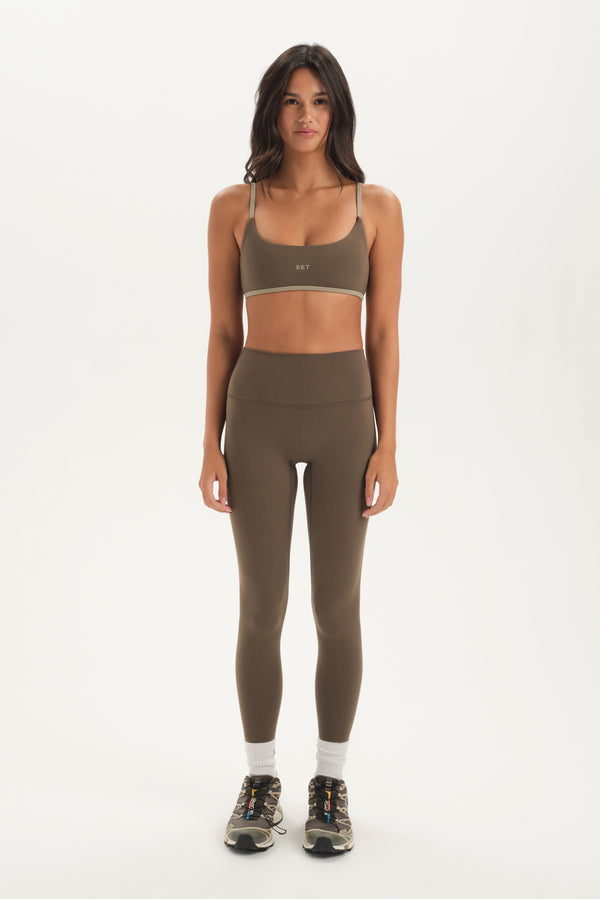 Woman wearing a green sports bra and leggings set on a white background