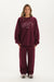 Person wearing a maroon 'SET' sweatshirt and pants on a white background