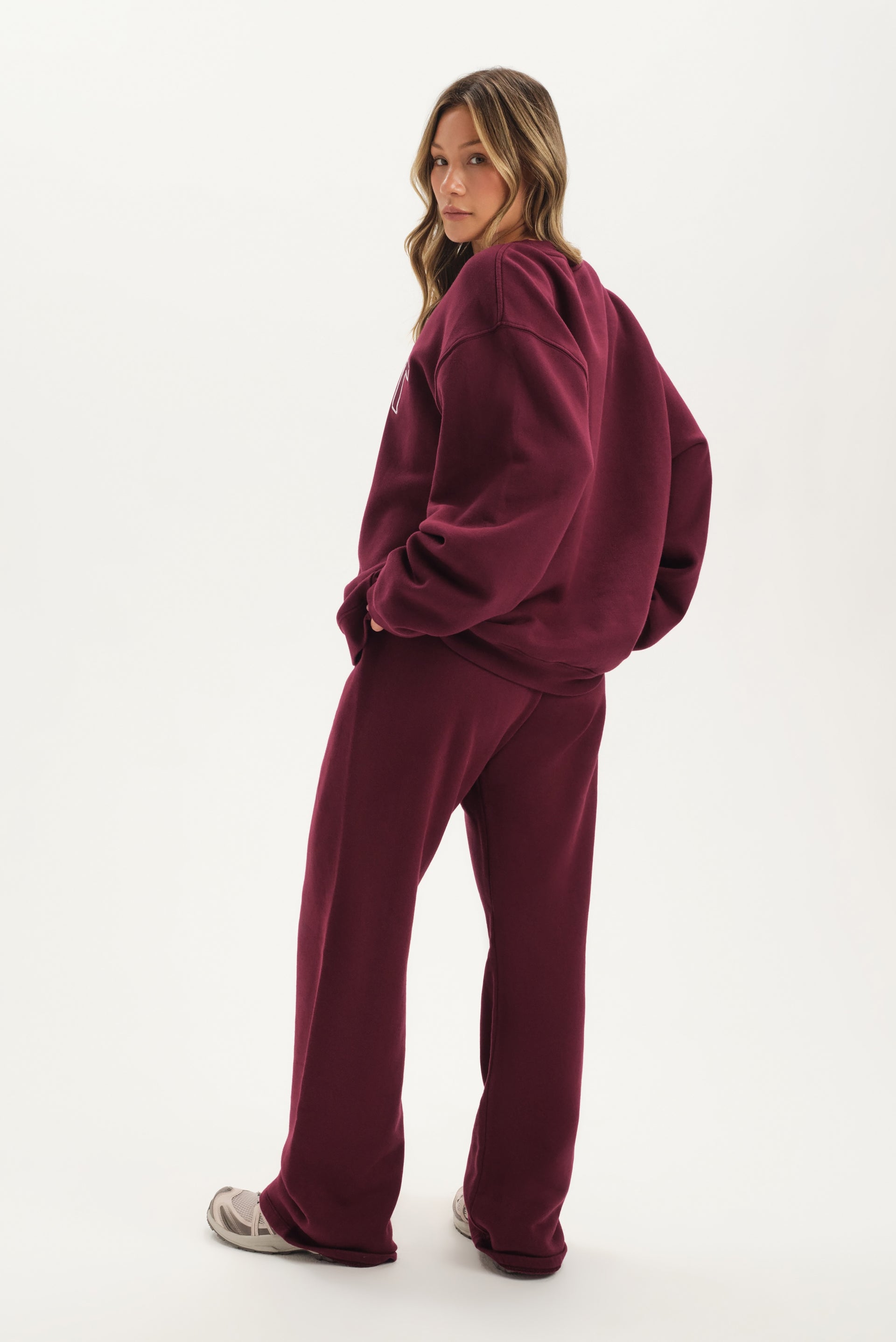 Person wearing a burgundy tracksuit on a white background