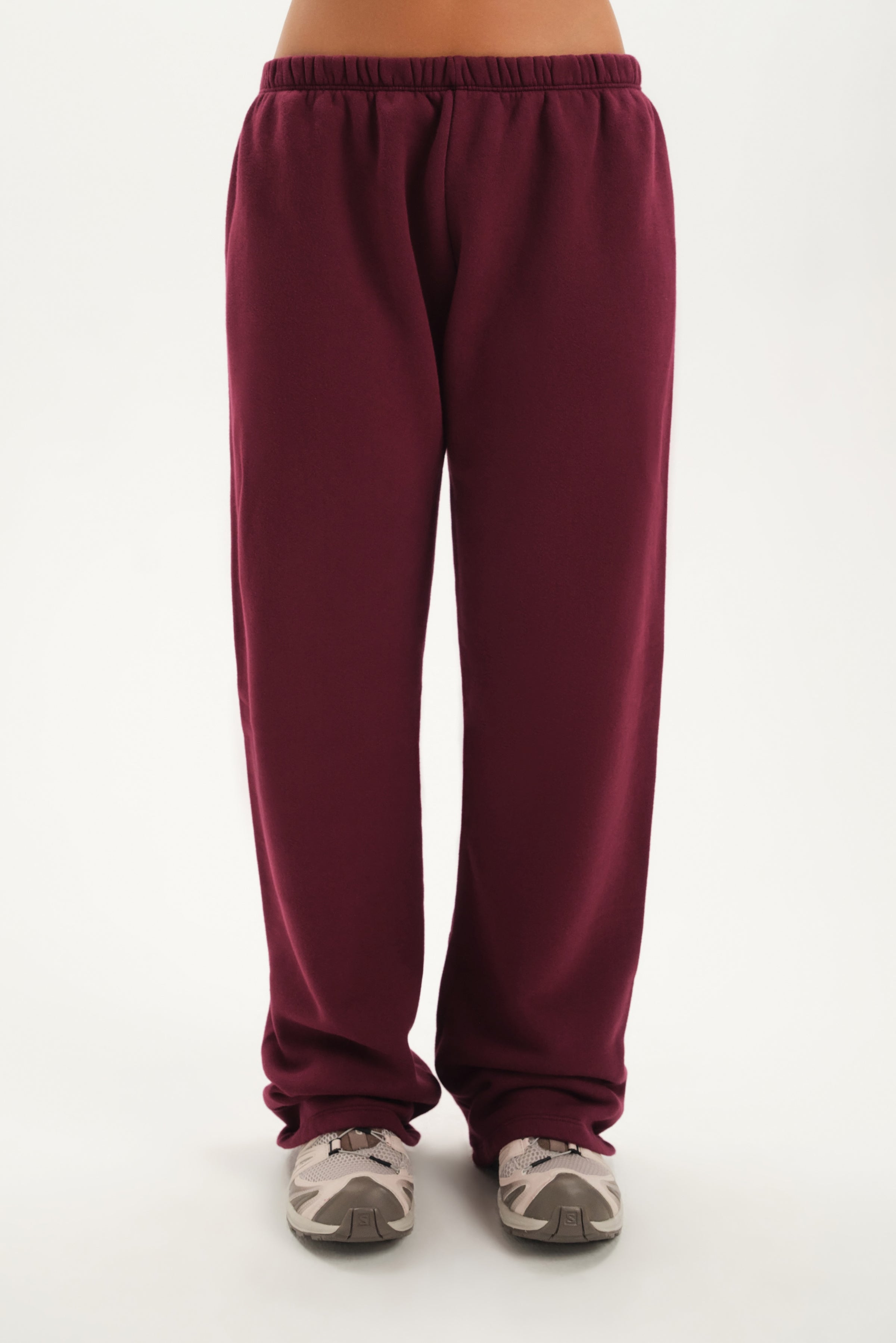 Maroon sweatpants worn by a person on a white background 