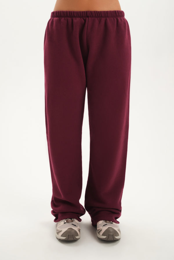Maroon sweatpants worn by a person on a white background 