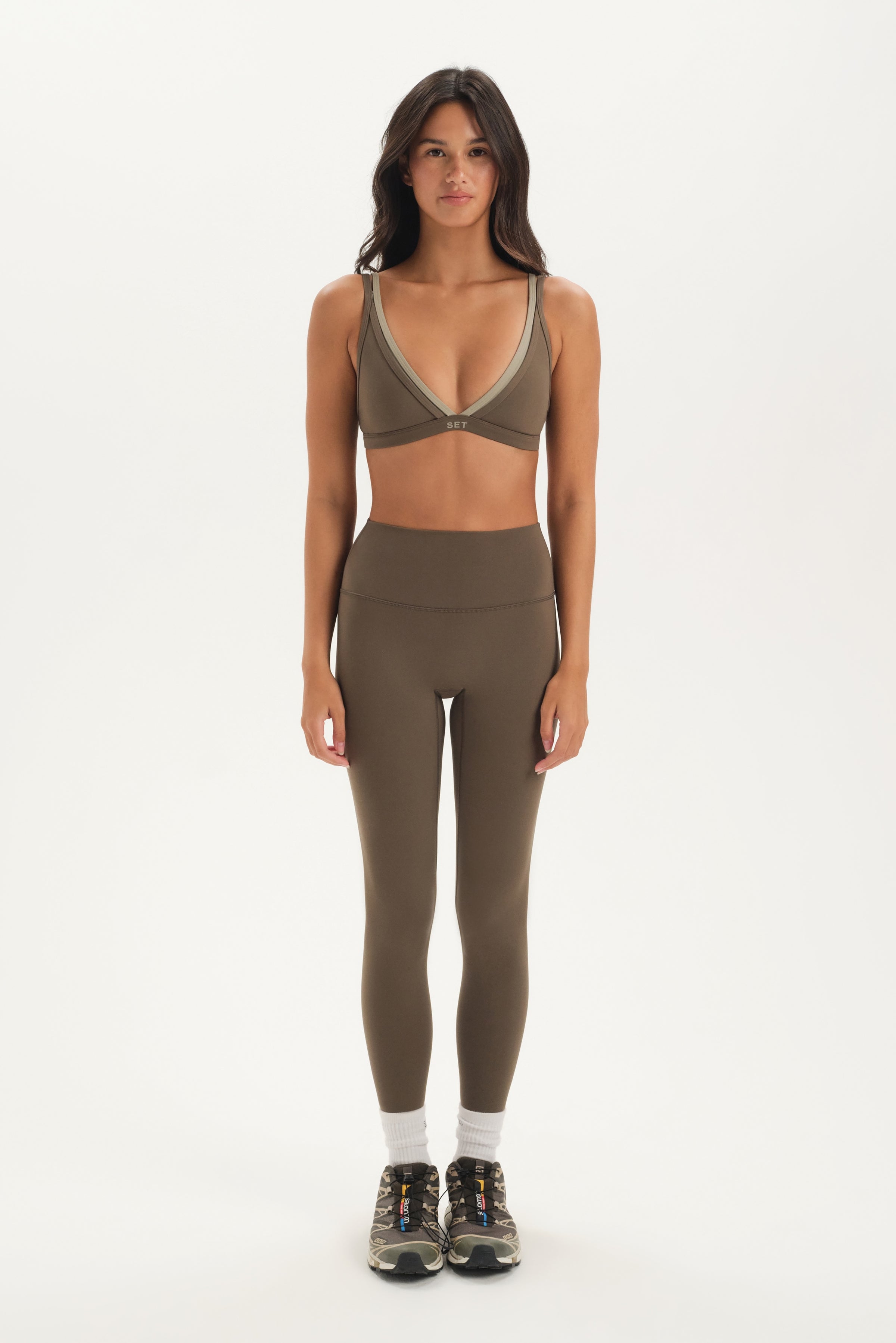 Woman wearing a green sports bra and leggings set on a white background