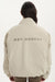 Person wearing a beige jacket with 'SET ACTIVE' text on the back against a white background