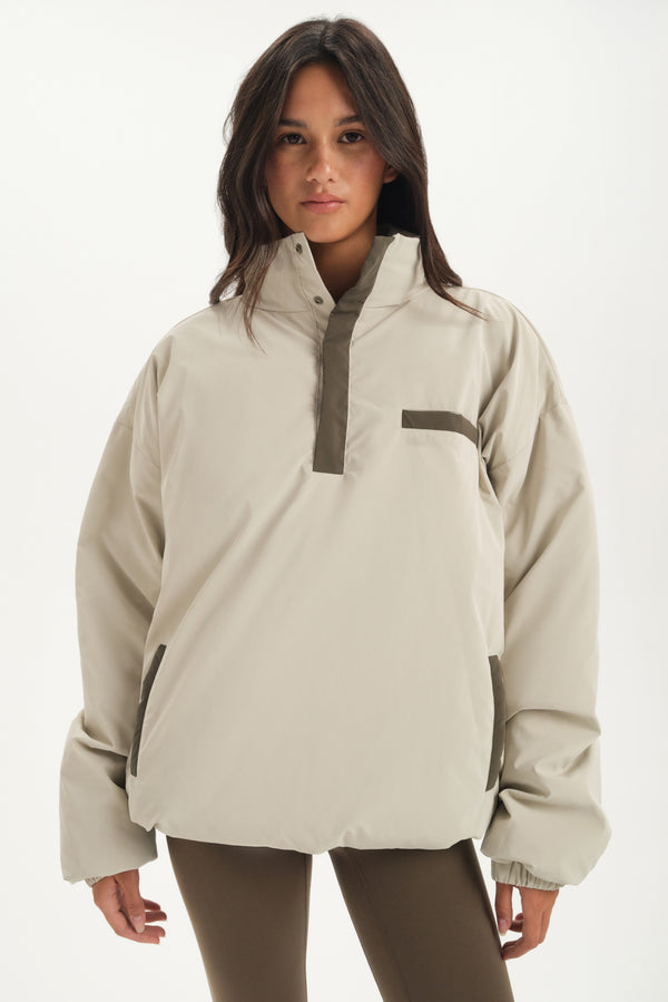Woman wearing a beige puffer with a white background 