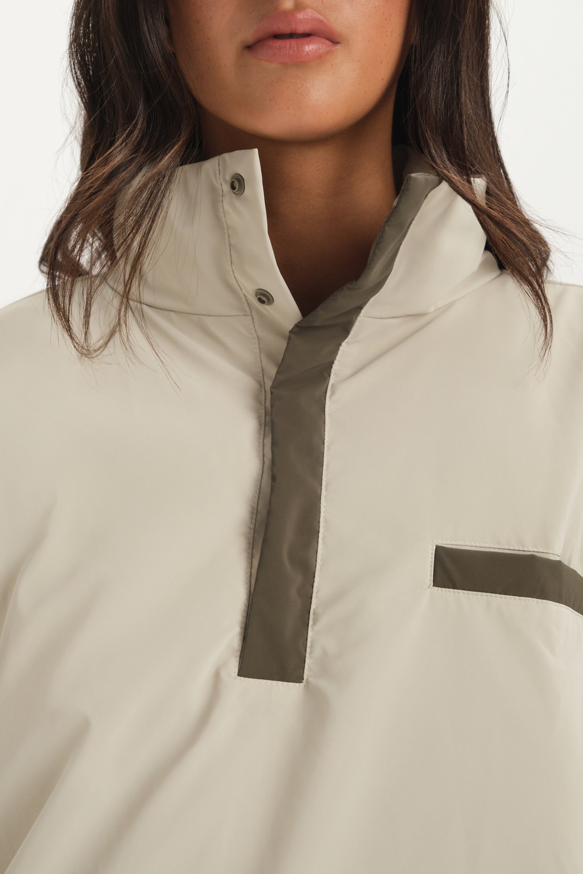 Close-up of a beige jacket with a high collar and dark trim on a white background