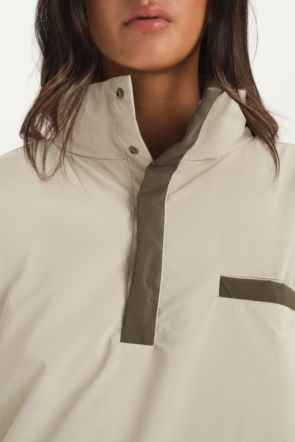 Close-up of a beige jacket with a high collar and dark trim on a white background
