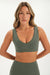 Woman wearing a green sports bra and leggings on a white background <model-info>Bre wears a size S and is 5’7”, 25½" waist, 33” bust.</model-info>
