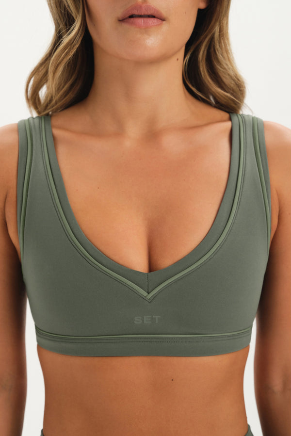 Green sports bra worn by a person on a plain background
