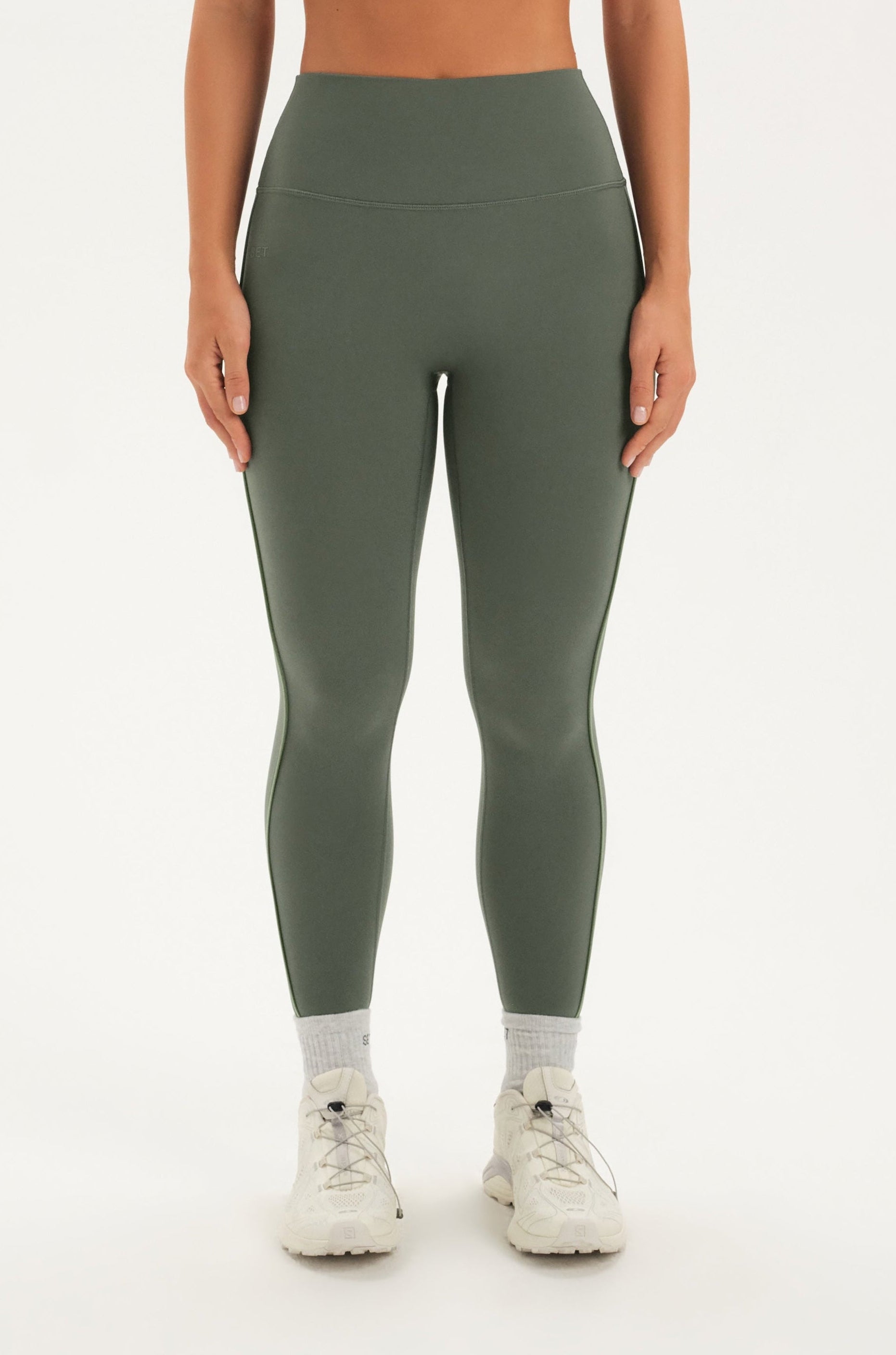 Woman wearing a green leggings on a white background 