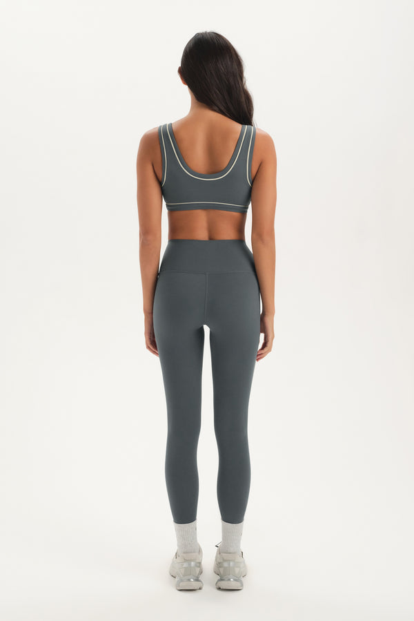Person wearing a gray sports bra and leggings set on a white background