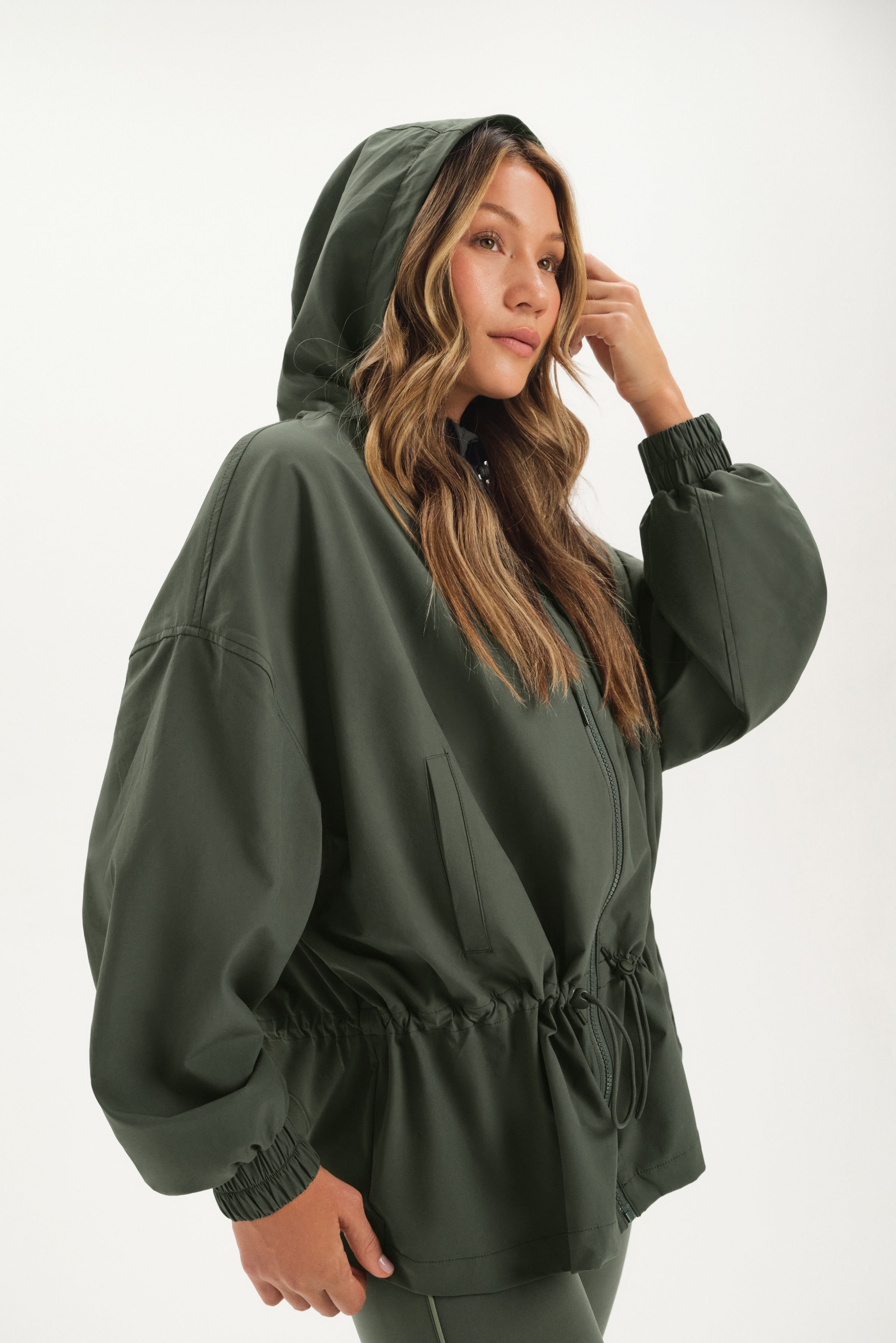 Person wearing a green hooded jacket on a white background