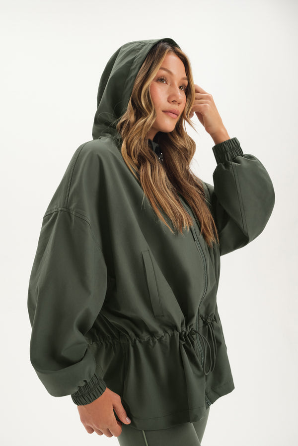 Person wearing a green hooded jacket on a white background