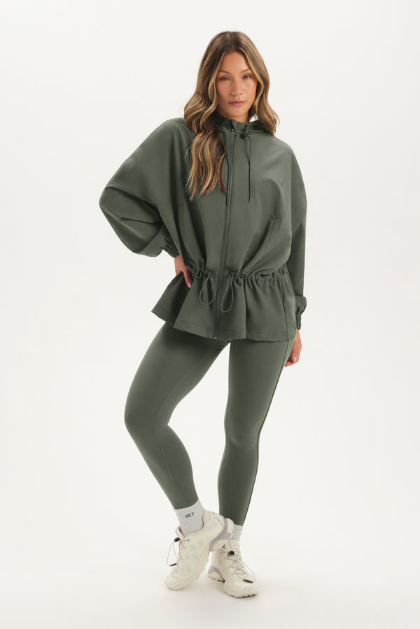 Woman wearing a green outfit with a matching jacket and leggings on a white background