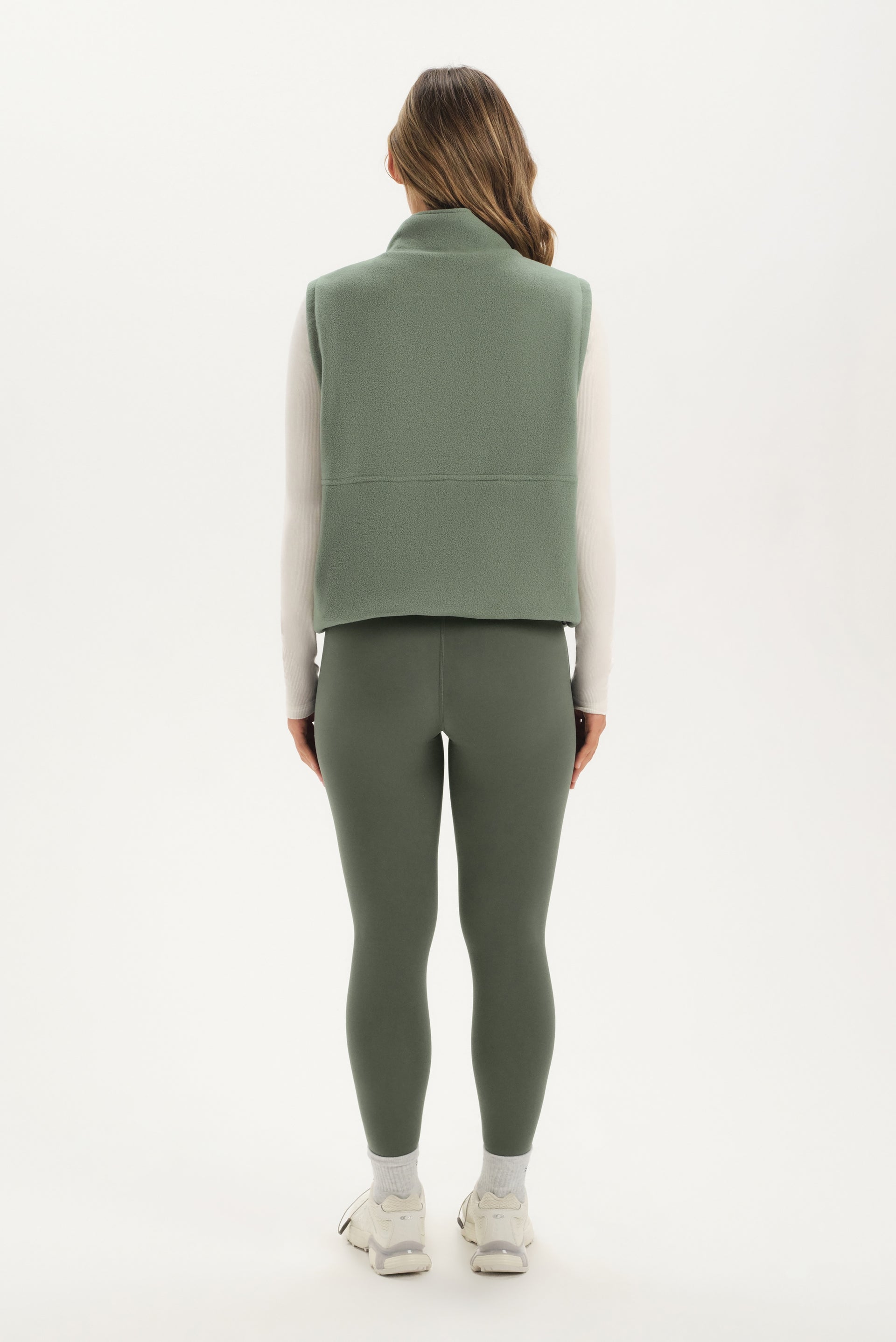 Person wearing a green vest and leggings set on a white background