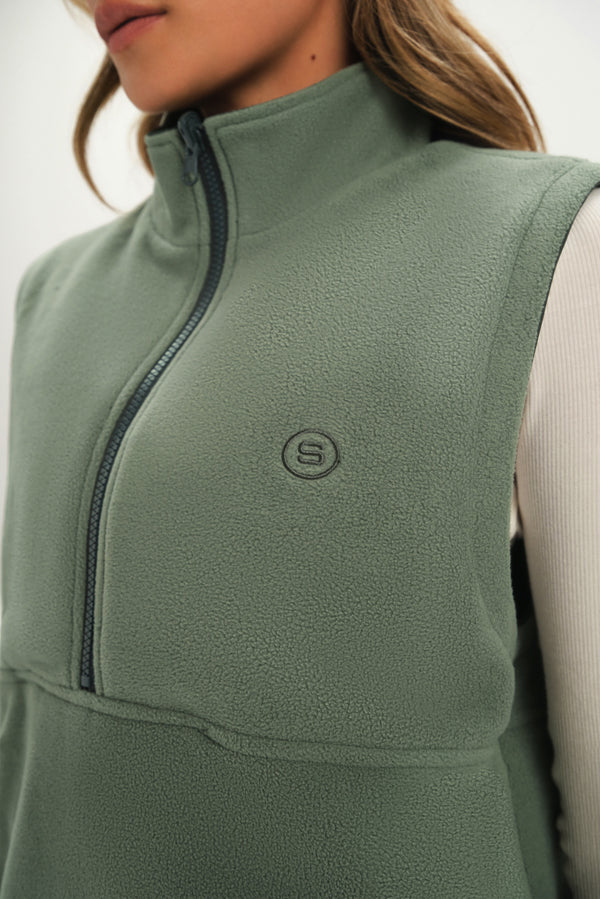 Green fleece vest with a brand logo on a neutral background