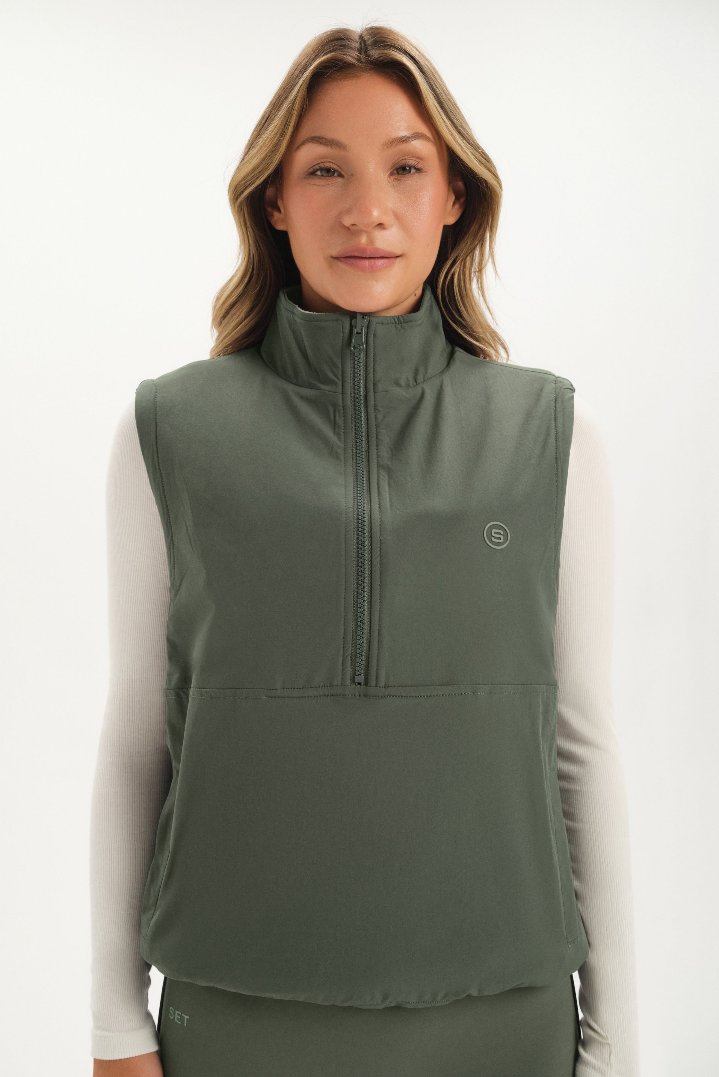 Woman wearing a green vest with a white background 