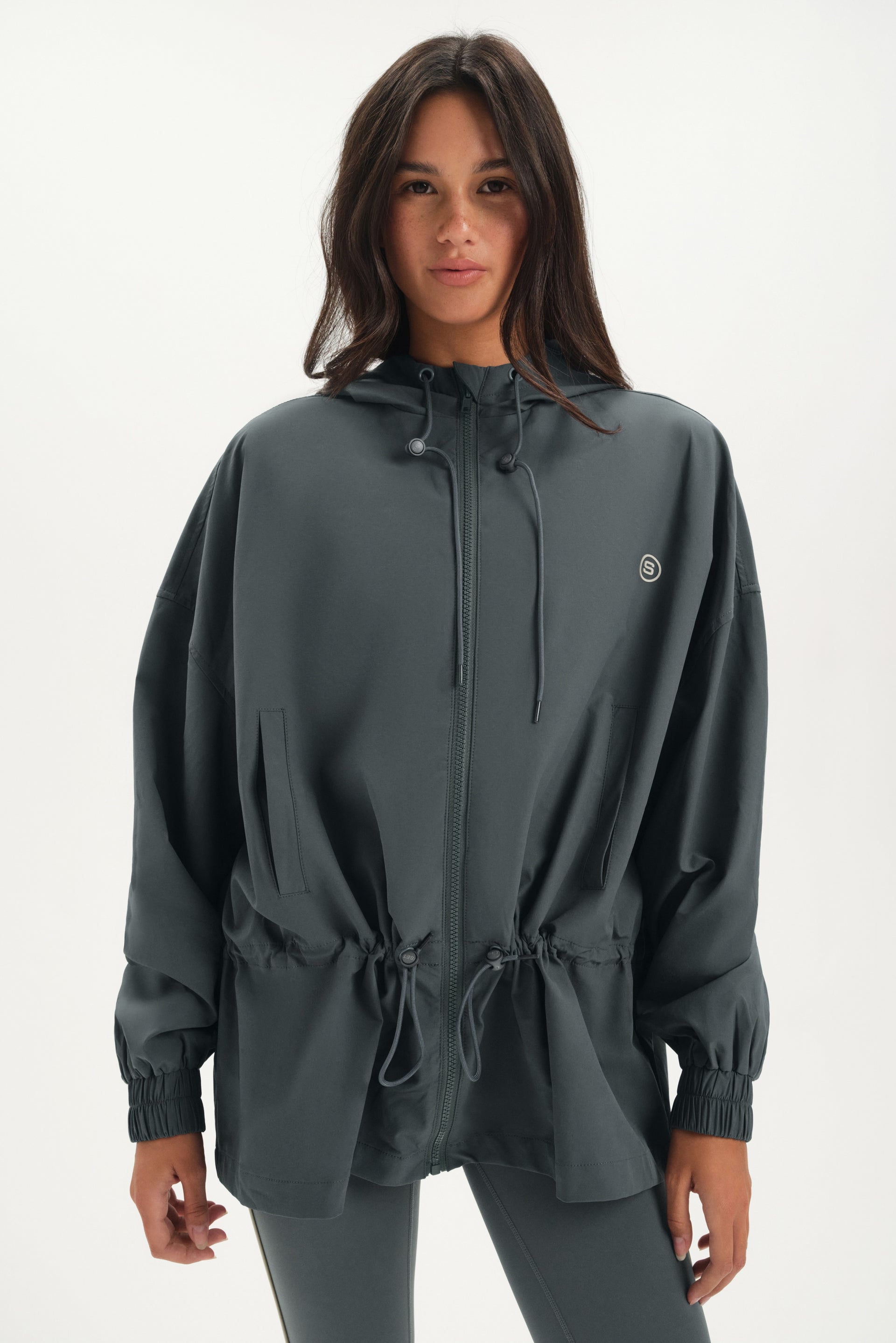 Person wearing a gray windbreaker on a white background <model-info>Jelene wears a size XS and is 5’7”, 23” waist, 32AB bust.</model-info>