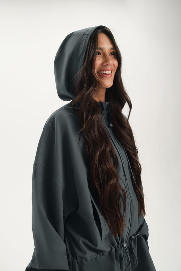 Woman wearing a dark gray hooded jacket on a white background