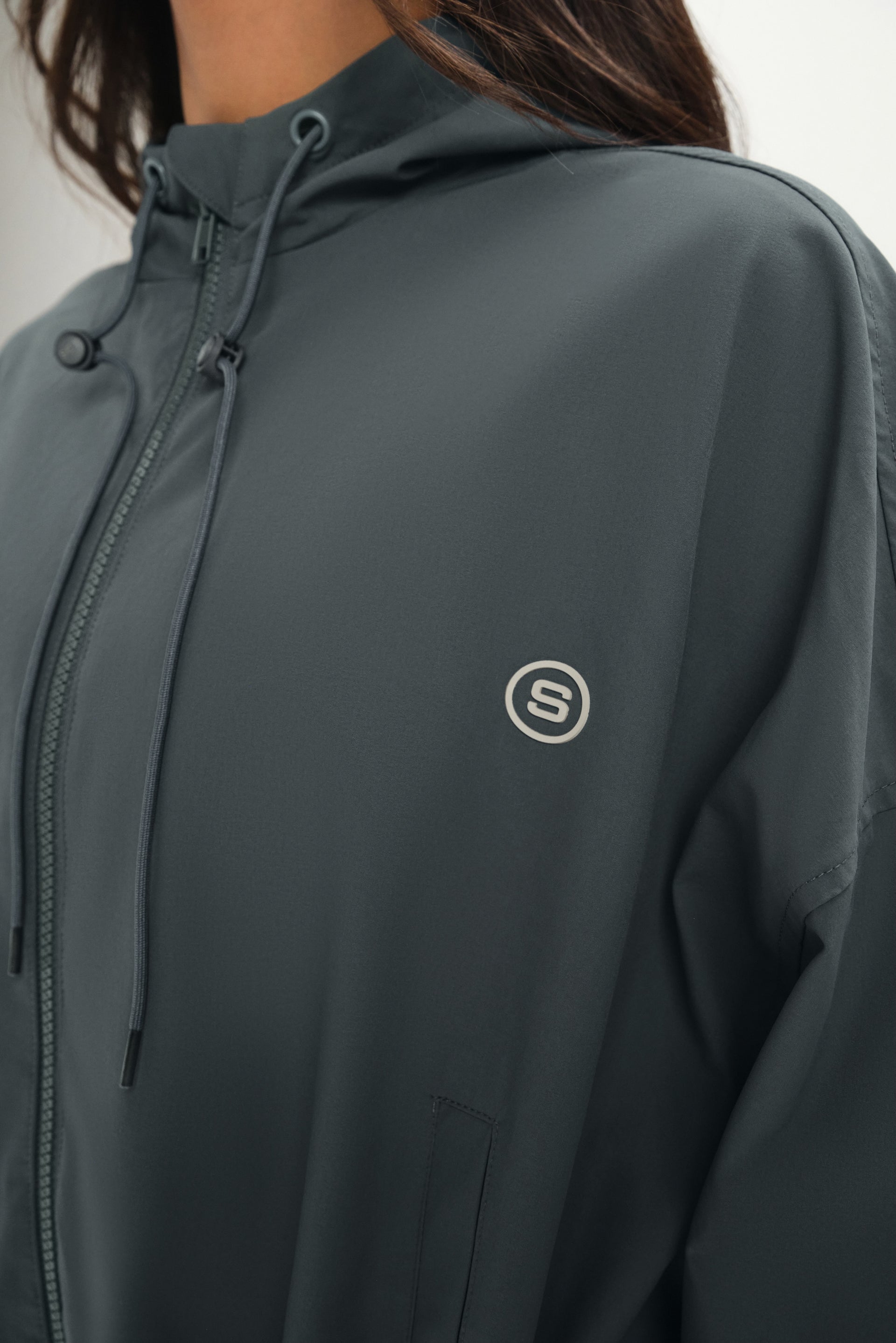 Dark gray jacket with a brand logo on a neutral background