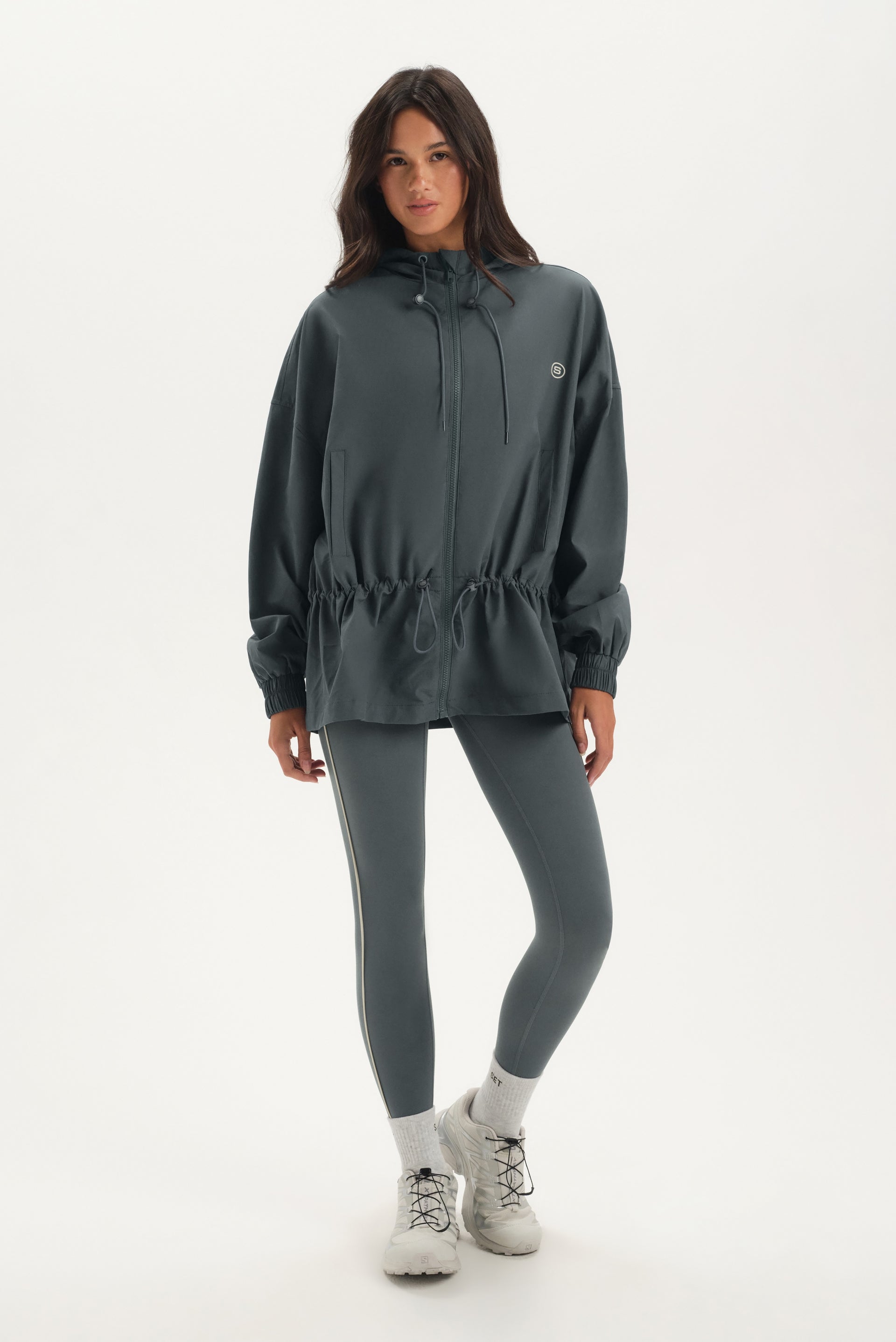 Woman wearing a dark gray jacket and leggings on a white background