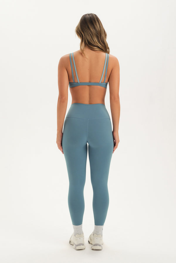 Person wearing a blue sports bra and leggings set on a white background