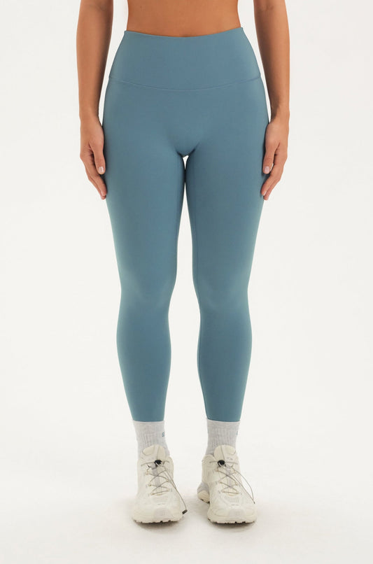 Woman wearing a blue leggings on a white background <model-info>Bre wears a size M and is 5’7”, 25½" waist, 33” bust.</model-info>