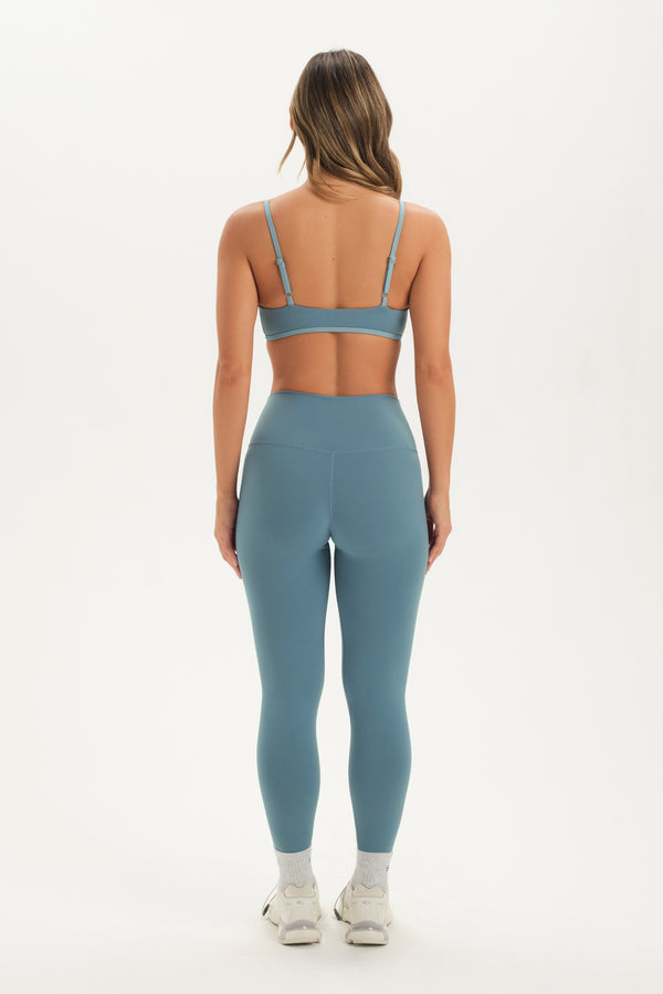 Person wearing a blue sports bra and leggings set on a white background