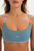 Woman wearing a blue sports bra with 'SET' branding on a plain background