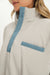 Close-up of a beige jacket with blue accents worn by a person.