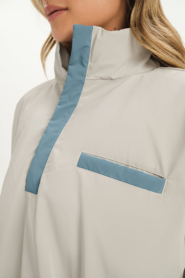 Close-up of a beige jacket with blue accents worn by a person.