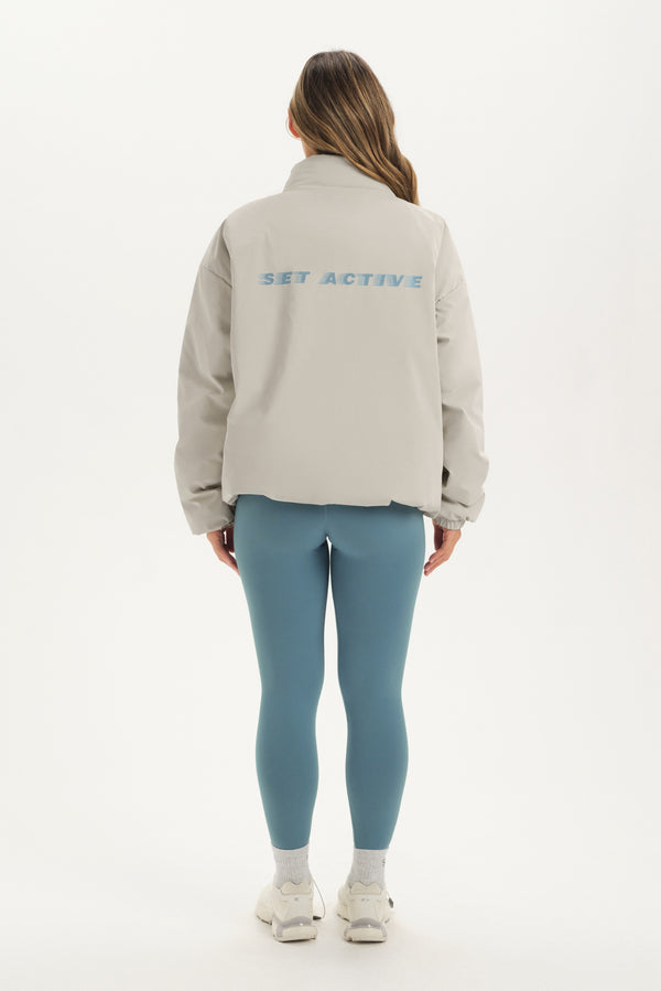 Person wearing a beige jacket with 'Set Active' text on the back, standing against a white background