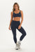 Woman wearing a navy sports bra and leggings set on a white background