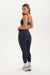Woman wearing a navy sports bra and leggings set on a white background