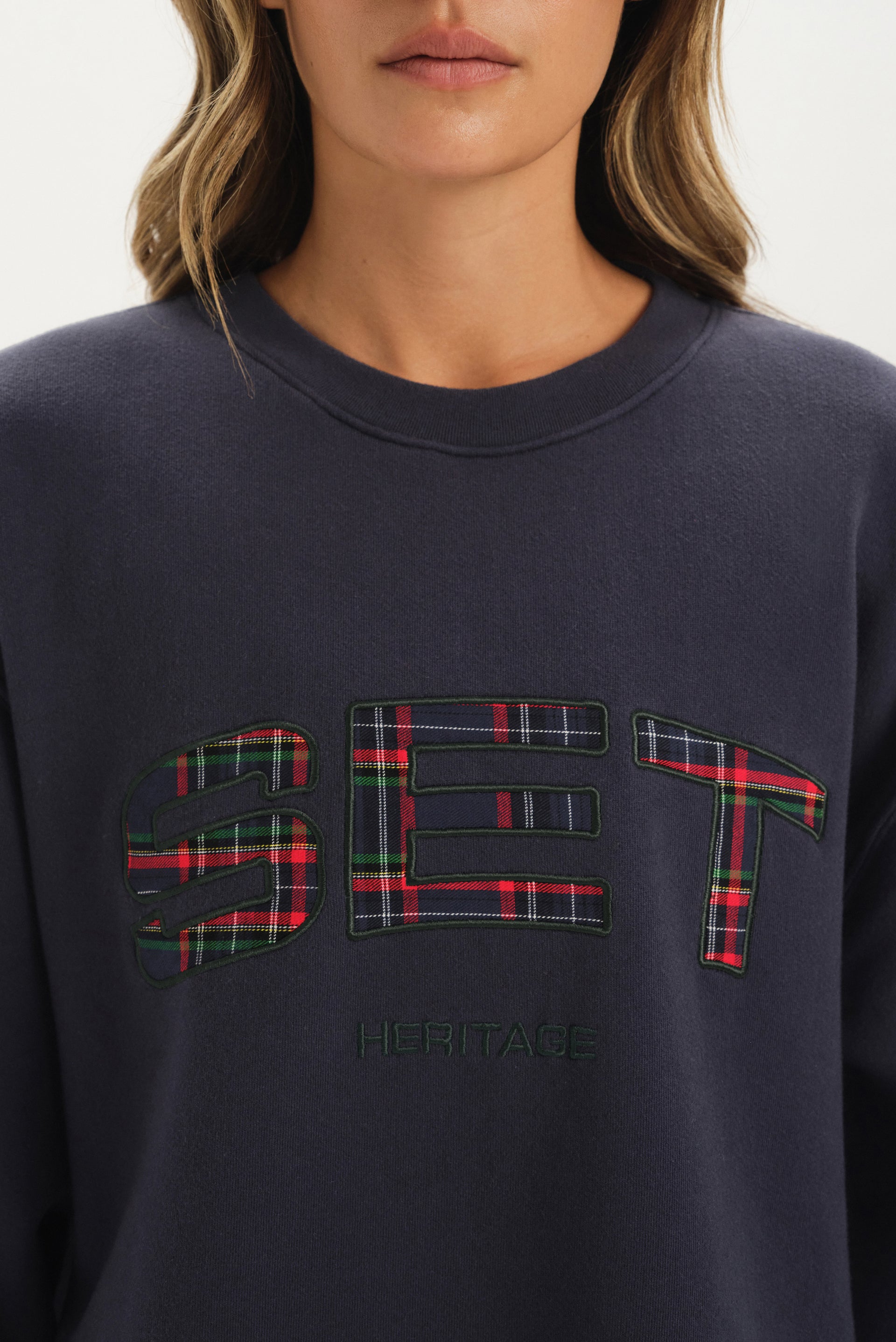 Navy sweatshirt with plaid 'SET' logo worn by a person