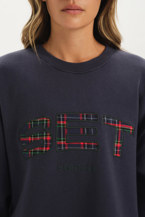 Navy sweatshirt with plaid 'SET' logo worn by a person