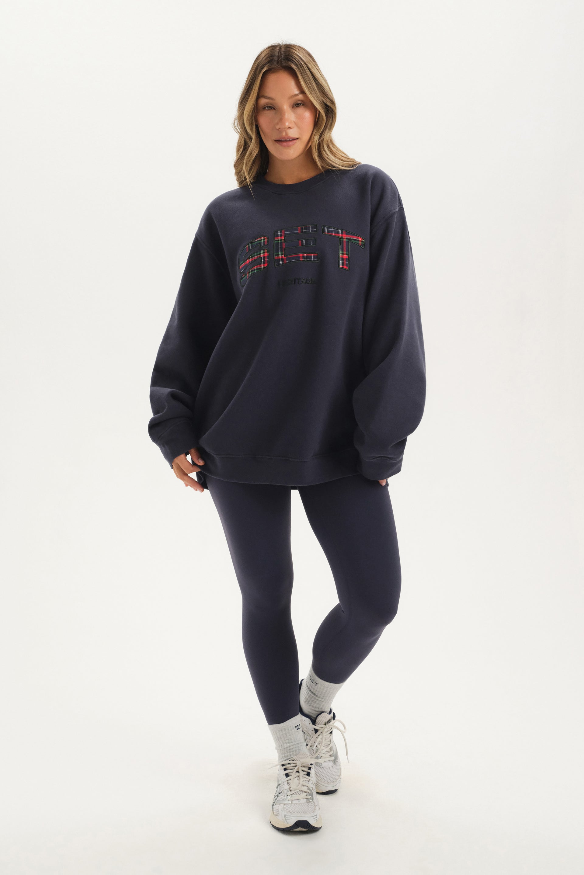 Woman wearing a navy oversized sweatshirt and leggings on a white background