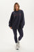 Woman wearing a navy oversized sweatshirt and leggings on a white background