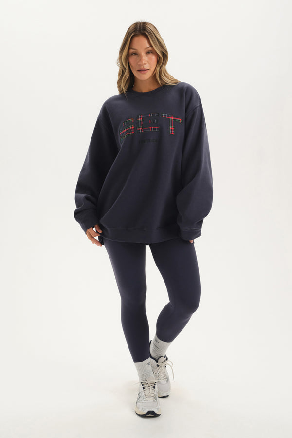 Woman wearing a navy oversized sweatshirt and leggings on a white background